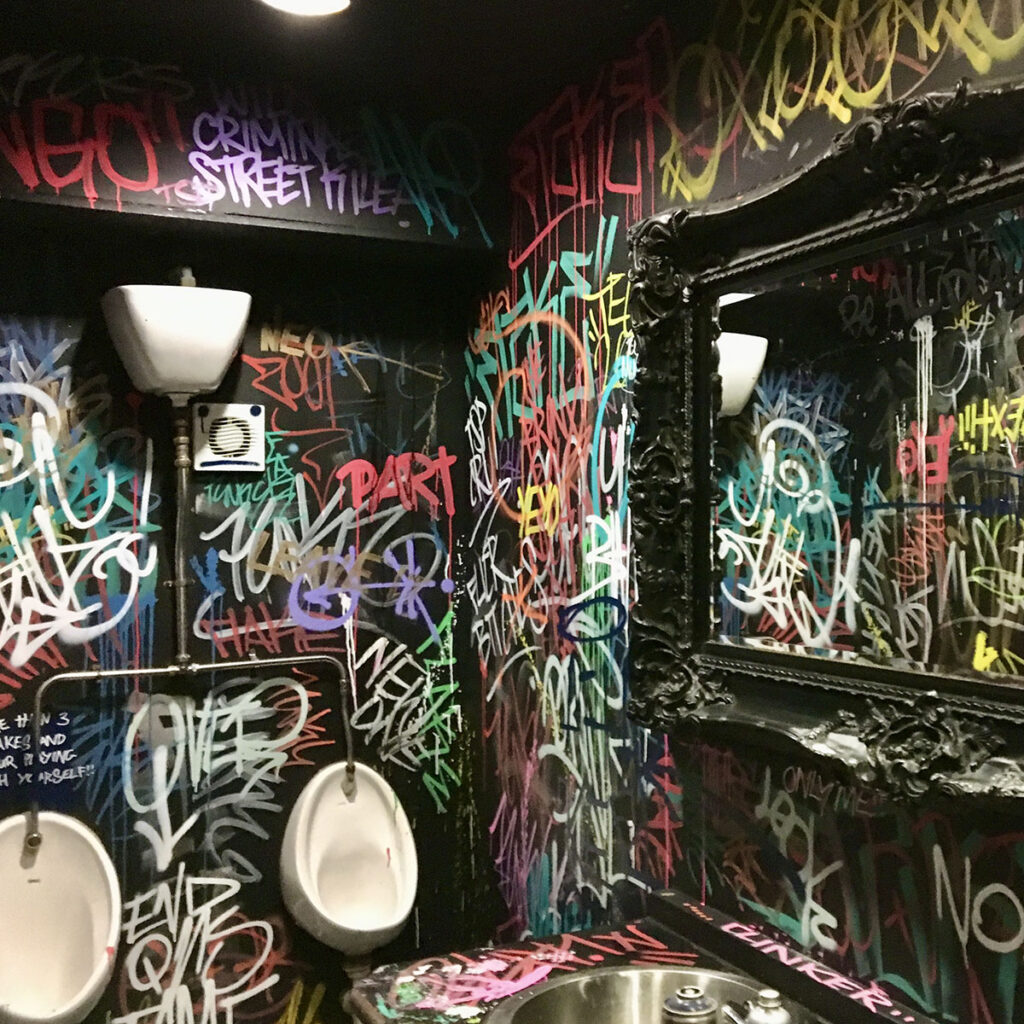 Graffiti-bombed toilet walls at Smack Nightclub in Leamington Spa, covered floor to ceiling in layered tags and colourful street-style lettering.