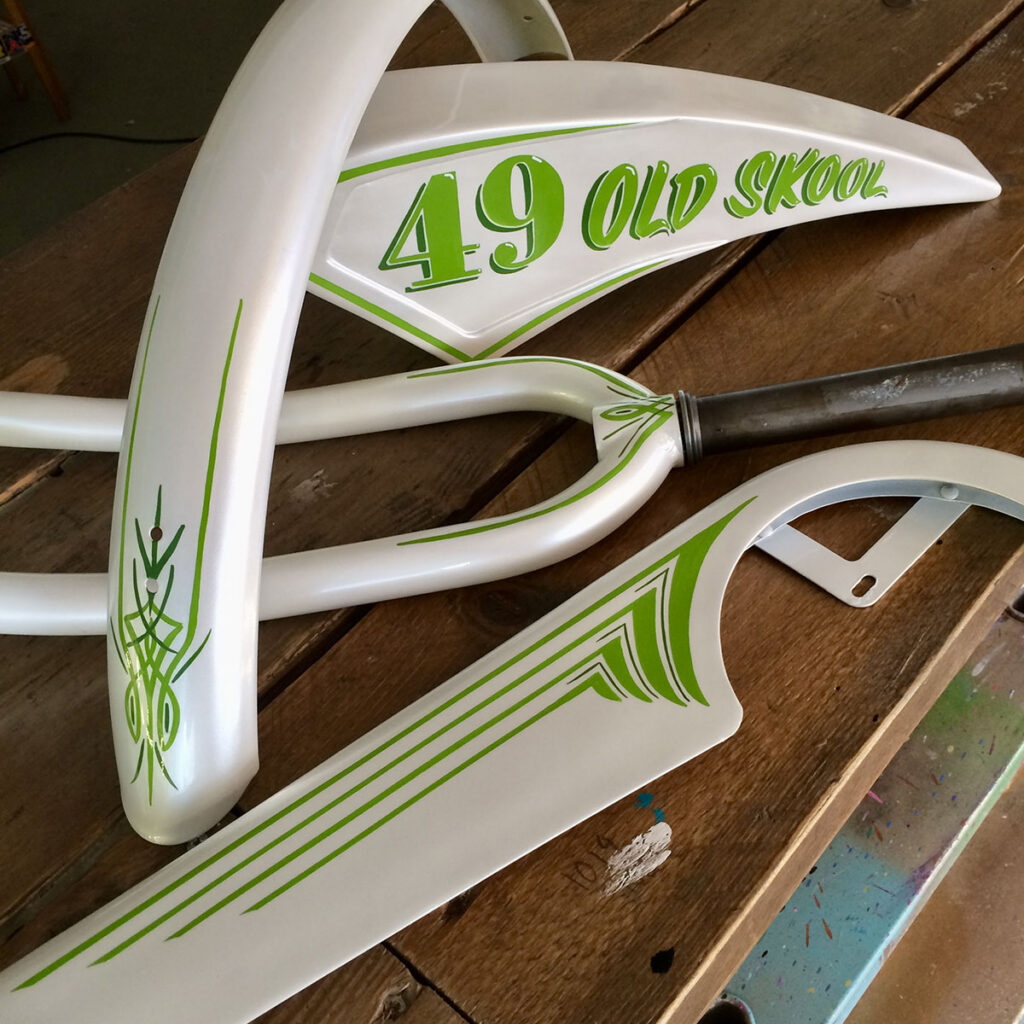 Hand-painted vintage bike parts laid out on a workbench, featuring green pinstriping and “49 Old Skool” lettering.