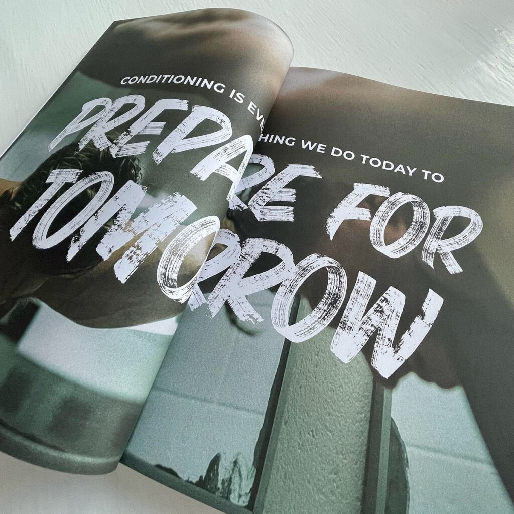 Double page spread from the Gymshark internal brand book featuring bold hand painted brush lettering reading “Prepare for Tomorrow”, showcasing bespoke typography created by Seven 9 Signs and later digitised for brand use.