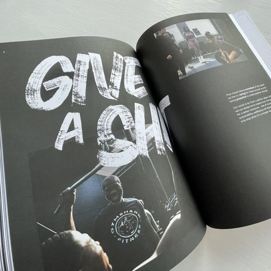 Hand rendered brush lettering reading “Give A Sh” on a Gymshark brand book spread, showcasing custom hand painted typography created by Seven 9 Signs and later digitised for internal brand use.