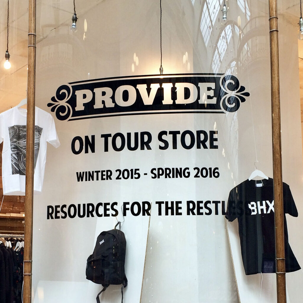 Hand-painted window lettering for Provide’s pop-up store, featuring bold black lettering and decorative details across the glass window display. 
