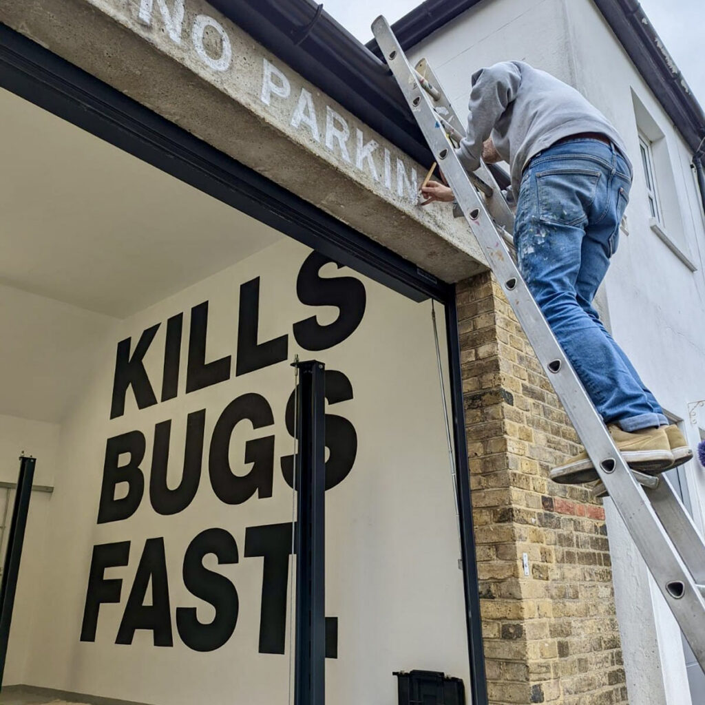 Hand-painted typography for a private client in Windsor, featuring bold black lettering reading “Kills Bugs Fast” inside the space and a reclaimed-style “No Parking” detail above the entrance.