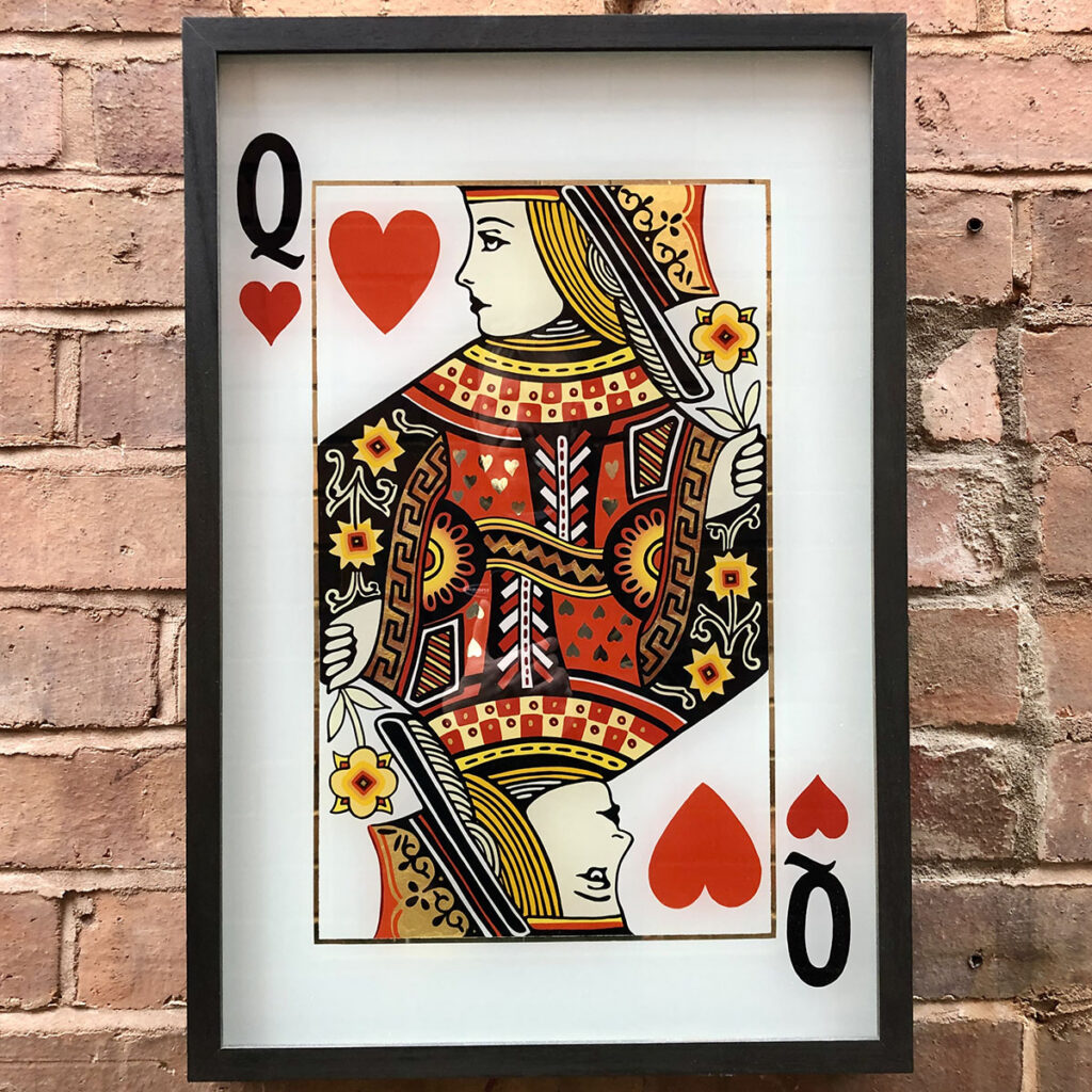 Reverse-painted Queen of Hearts artwork featuring deep gold, moon gold, lemon gold and variegated gold leaf, creating a vibrant mirrored finish on glass against a brick backdrop.