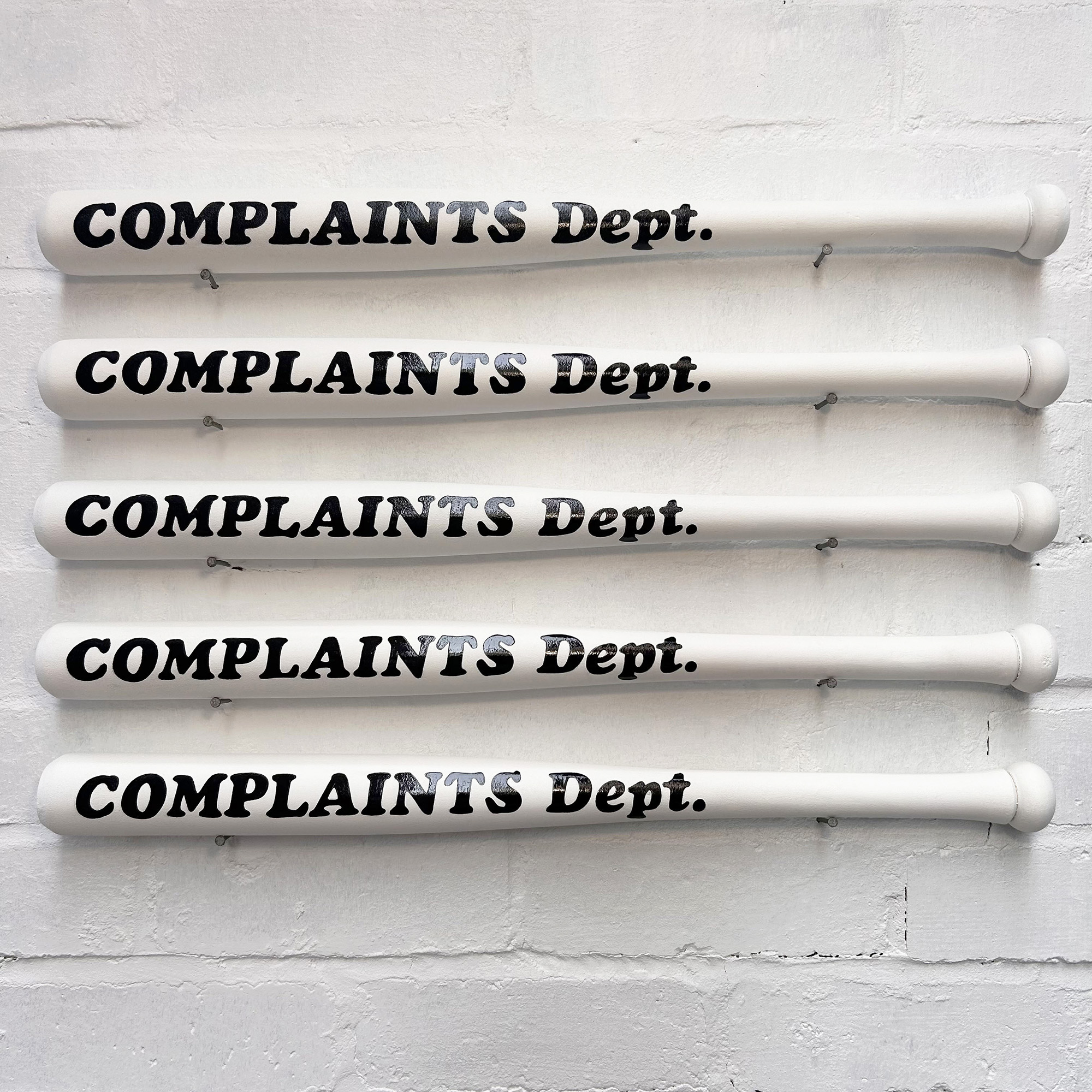 Conversation Piece: White hand painted Complaints Dept bat displayed on wall